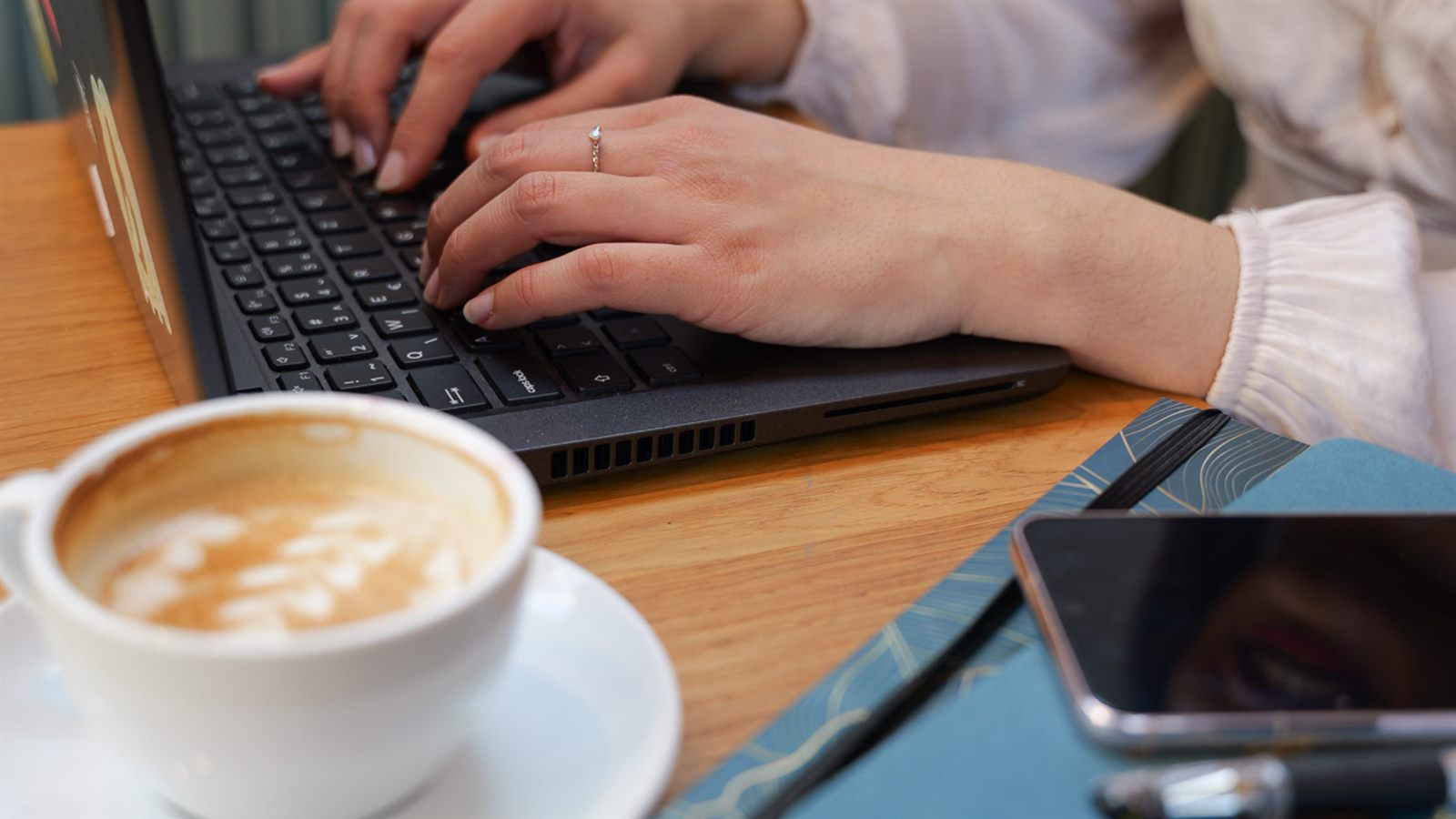 Hands typing on a laptop at a workspace